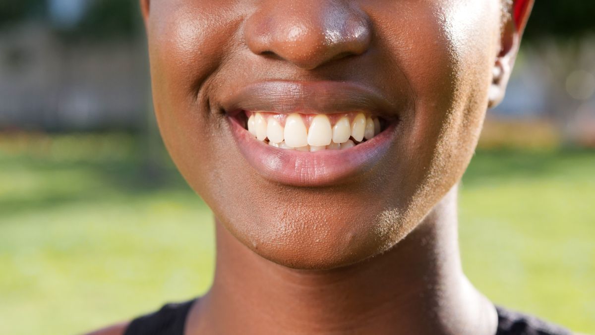 A close-up of a woman smiling, showing healthy natural teeth