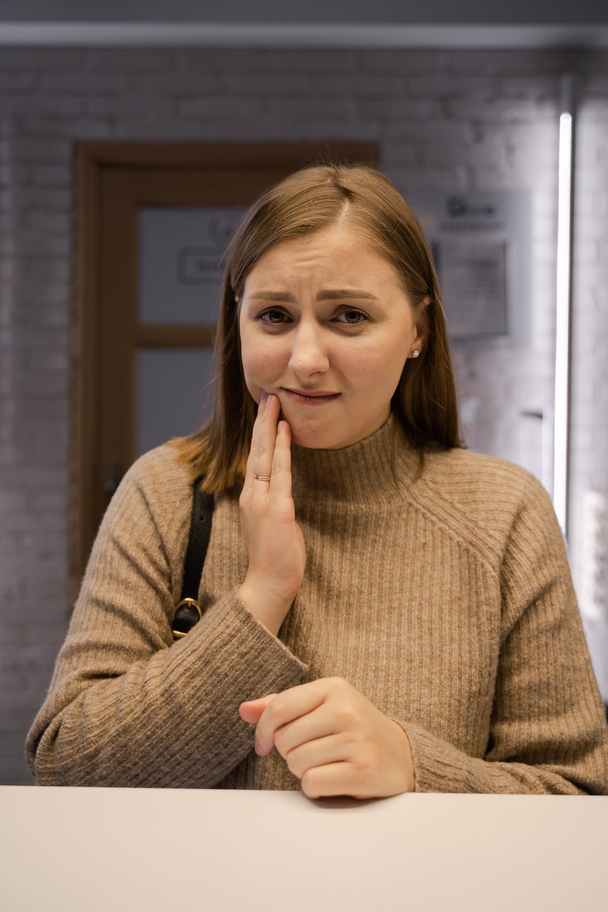 A woman holding her jaw, wincing from tooth pain